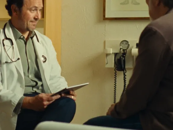 A clinician with a tablet consulting a patient in an exam room