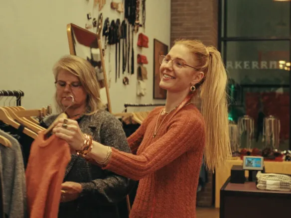 A retail associate helping a customer with a garment in a clothing store